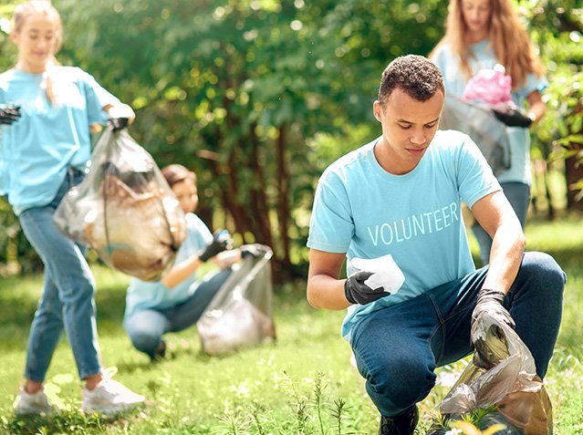 Volunteering. Young people volunteers outdoors africa boy close-up picking litter into plastic bag concentrated blurred Volunteering. Young people volunteers outdoors africa boy close-up picking litter into plastic bag concentrated blurred