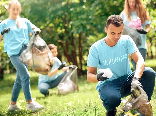 Volunteering. Young people volunteers outdoors africa boy close-up picking litter into plastic bag concentrated blurred Volunteering. Young people volunteers outdoors africa boy close-up picking litter into plastic bag concentrated blurred