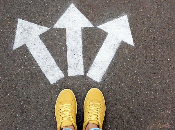 Woman standing near arrows on asphalt, top view. Choice concept